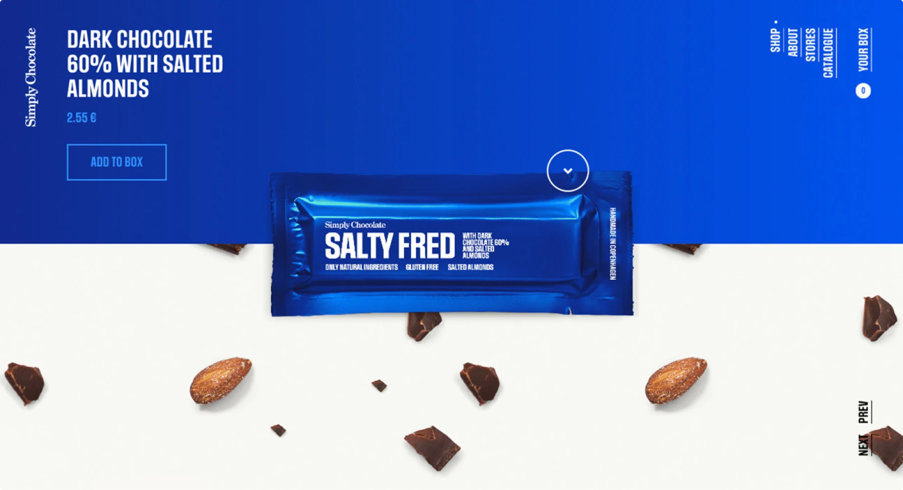 Screenshot of Simply Chocolate website showing "SALTY FRED" dark chocolate bar in vibrant blue packaging against blue background, with scattered chocolate pieces and salted almonds. Clean e-commerce interface displays "ADD TO BOX" button and €2.55 pricing