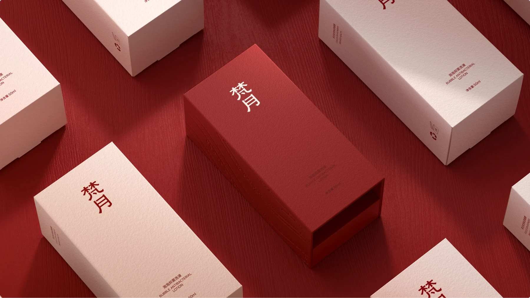 Monochromatic red packaging set on a red wood surface: a deep red sliding drawer box in the center surrounded by pale blush boxes with red Chinese typography, all in textured paper